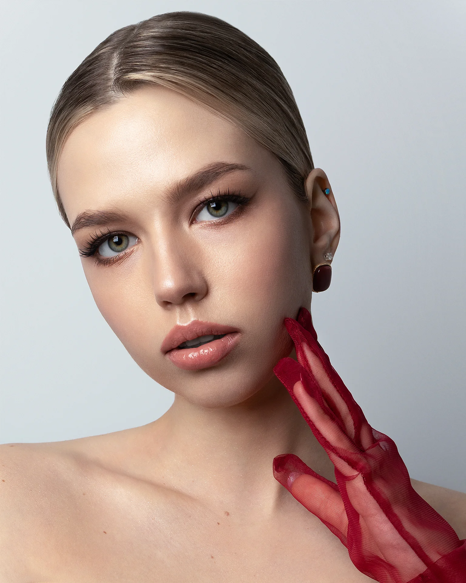 Retouched studio beauty portrait featuring red sheer gloves, precise dodge and burn, and preserved skin texture, photography by pnk.tata