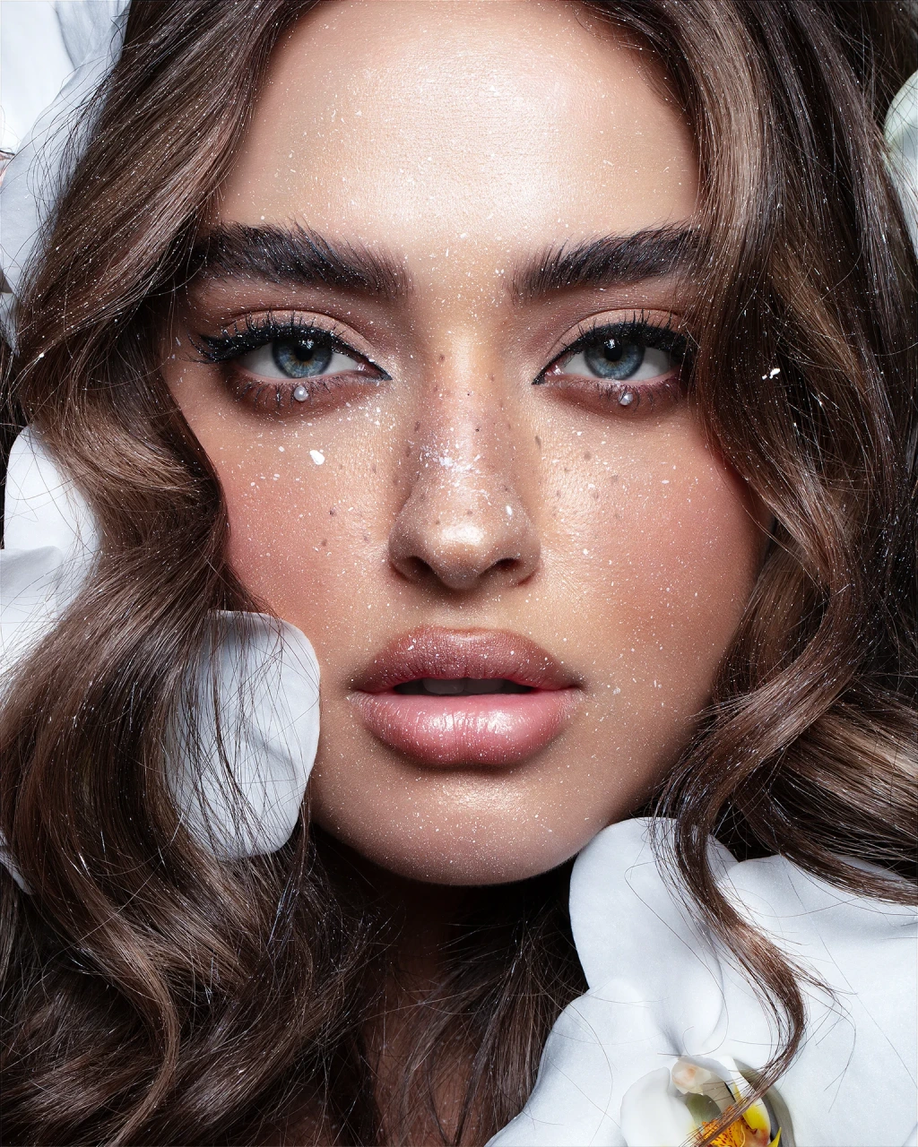 Close-up beauty portrait retouching of a model with orchid petals and glitter details, featuring dodge and burn, skin texture preservation, and color grading, photography by Abu Hayeh